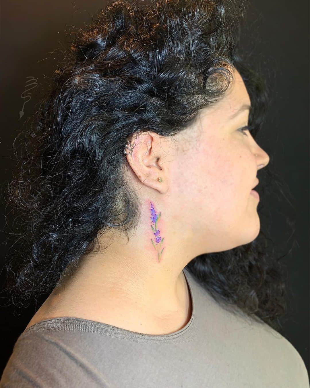 A colorful lavender tattoo behind the ear