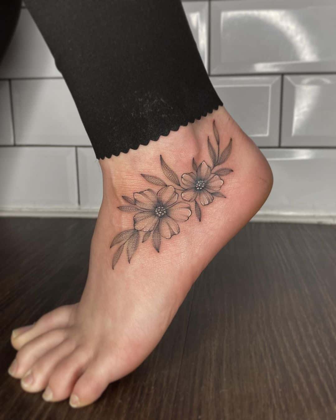 Fine line cherry blossom tattoo done on the ankle.