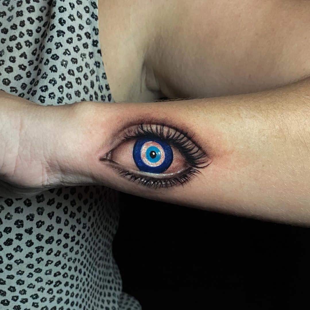 Ornamental evil eye tattoo on the sternum